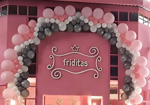 Arco de globos rosas, blancos y grises adornando la puerta del local de ropa Friditas