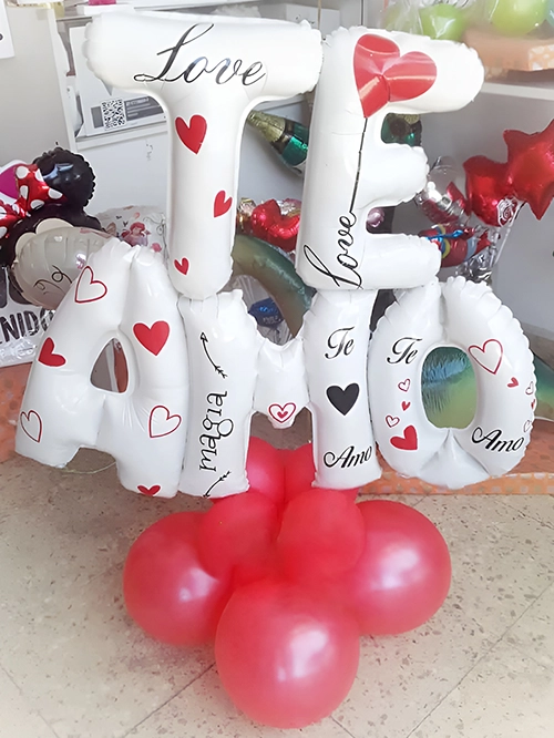 Bouquet blanco y rojo, globos de letras blancas estampadas con corazones, formando la palabra te amo sobre pequeña base de globos rojos