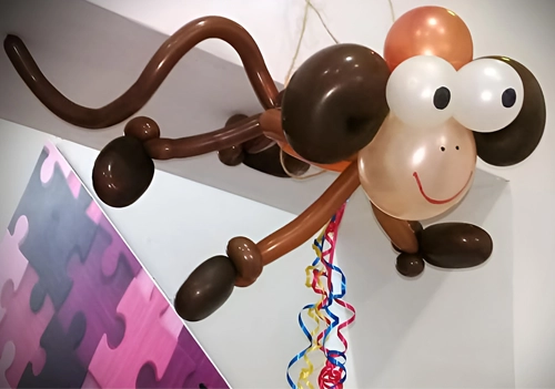 Mono hecho en globos de tonos marrones colgando del techo.